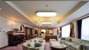 A spacious hotel room with a large seating area, a piano, and a dining table. - Hotel Showa Club (Atami)