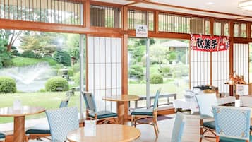 Un restaurant traditionnel de style japonais, doté d’un sol recouvert de tatamis, de meubles en bois et de grandes fenêtres donnant sur un jardin.