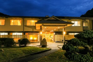 A two-story building with a covered entrance and a well-maintained garden. - Ichinomata Onsen Grand Hotel (Shimonoseki)
