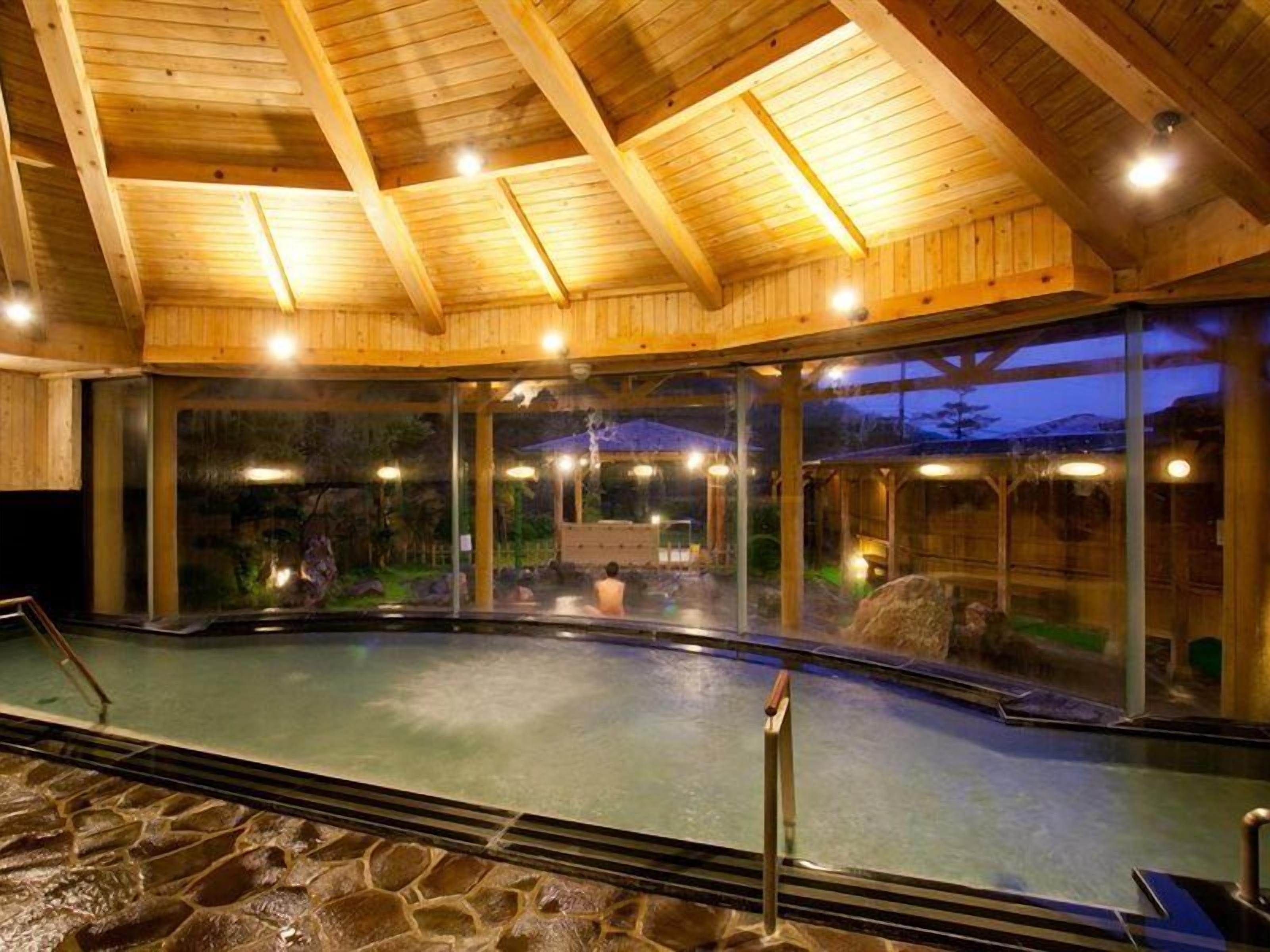 An indoor swimming pool with a wooden ceiling and glass walls.
