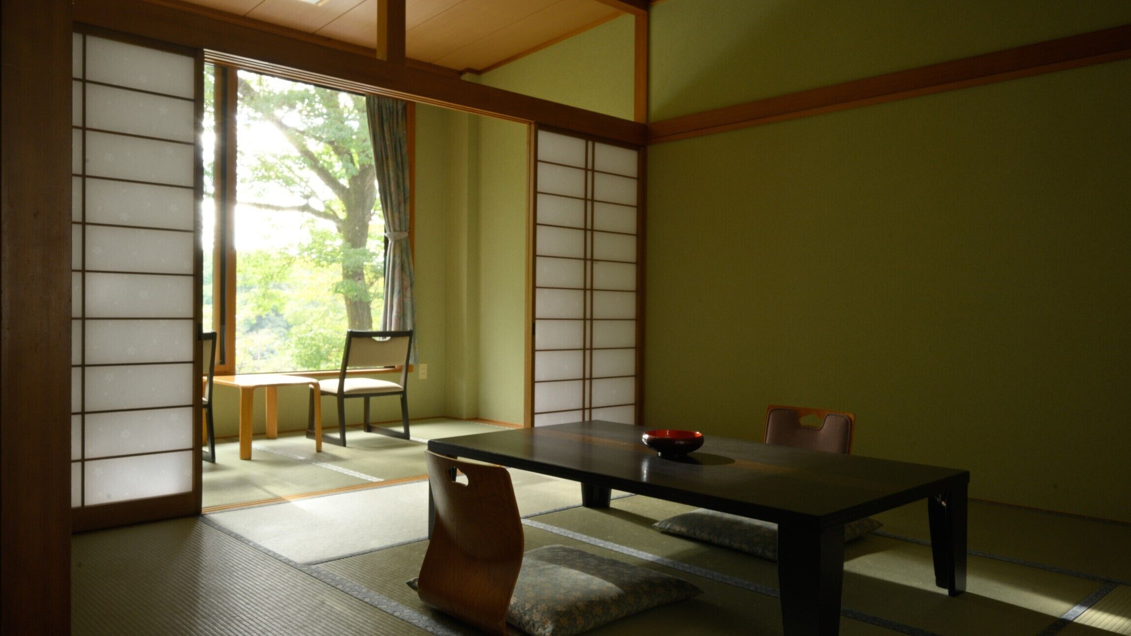 Una habitación japonesa tradicional con suelo de tatami, una mesa baja y puertas correderas.