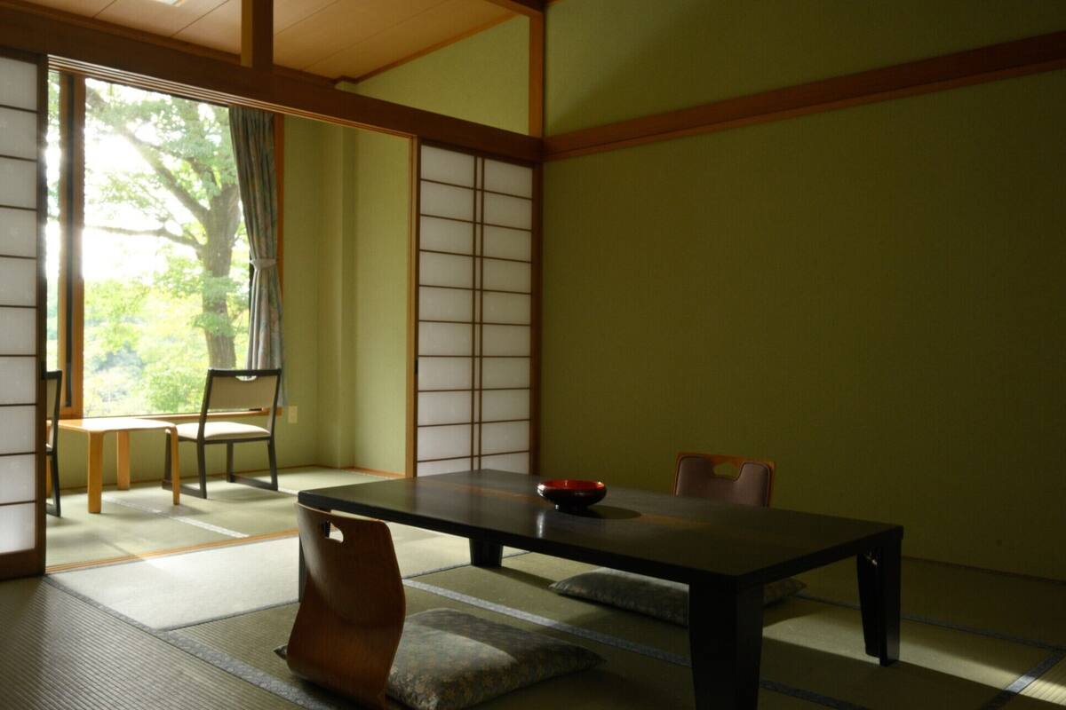 A traditional Japanese room with tatami flooring, a low table, and sliding doors.