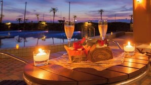 A table with a dessert, two glasses of champagne, and candles, overlooking a pool at dusk. - Boyokaku (Amakusa)