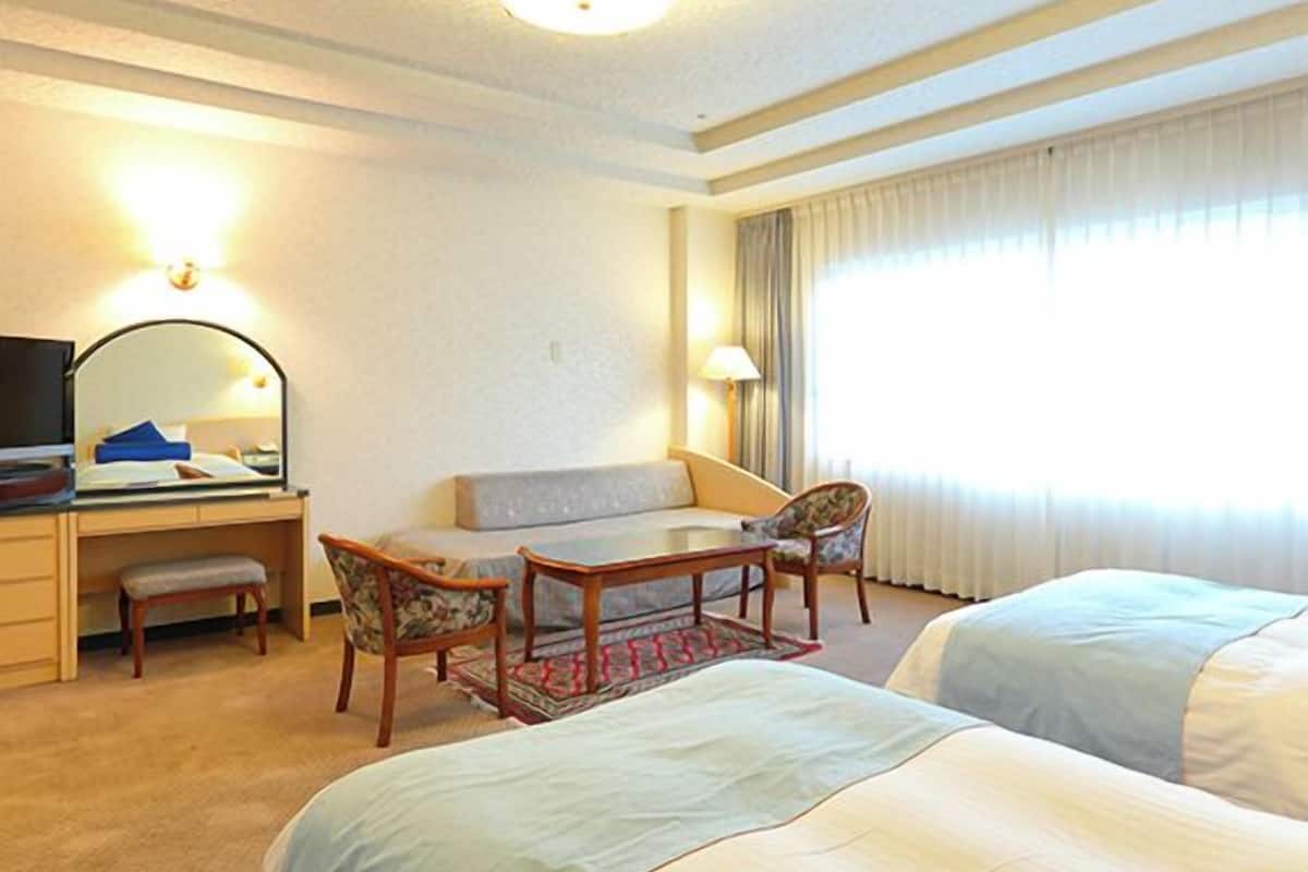 Una habitación de hotel con un escritorio, dos sillas, un sofá y dos camas.