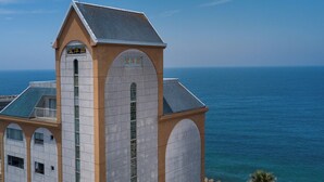 A building with a prominent tower, arched windows, and a view of the sea. - Boyokaku (Amakusa)