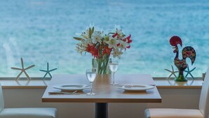 A dining table with a vase of flowers, two starfish decorations, and a view of the ocean. - Boyokaku (Amakusa)