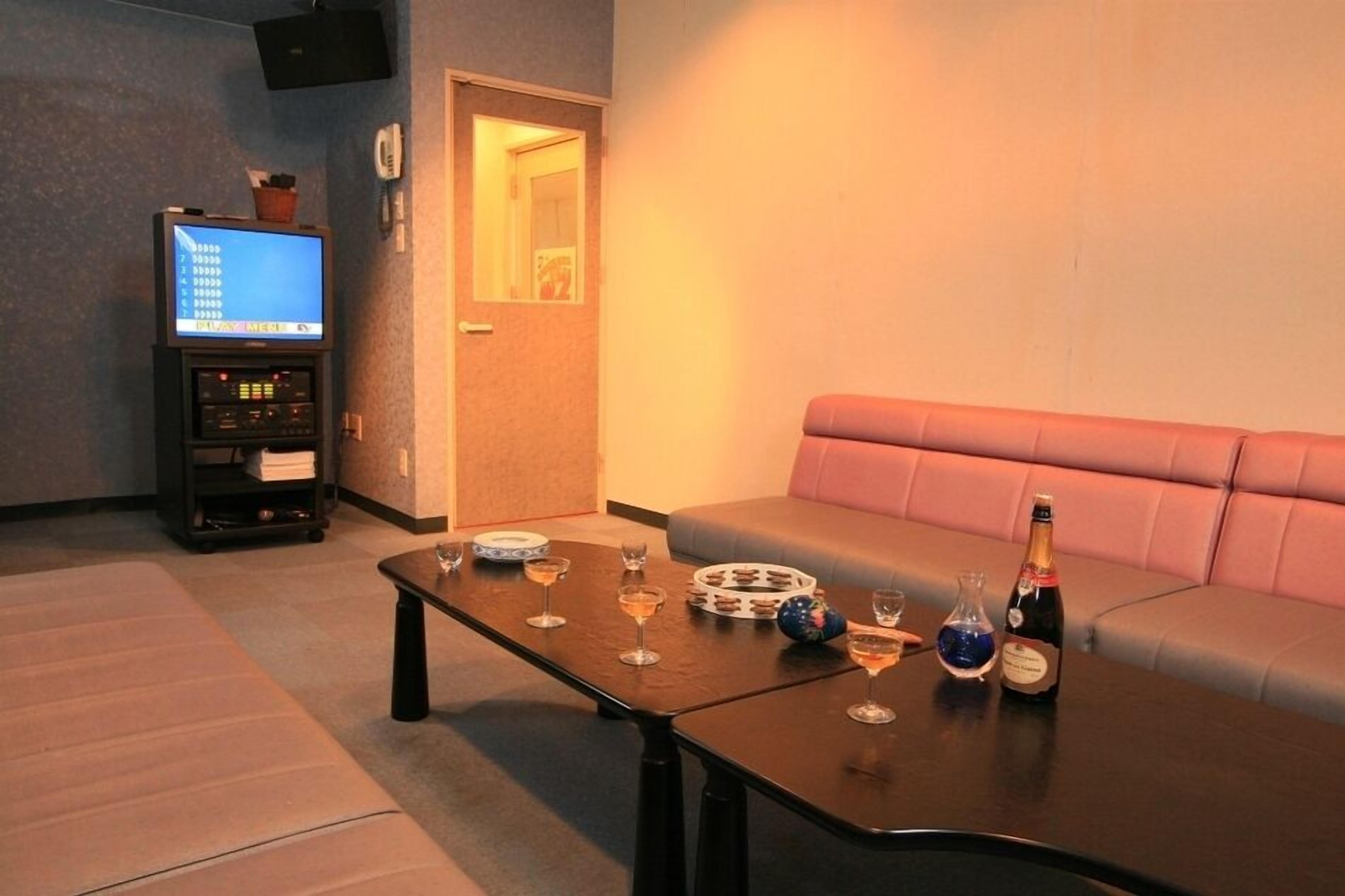A living room with a sofa, a coffee table with drinks, a television, and a small cabinet.