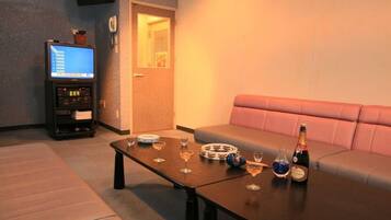 A living room with a sofa, a coffee table with drinks, a television, and a small cabinet.