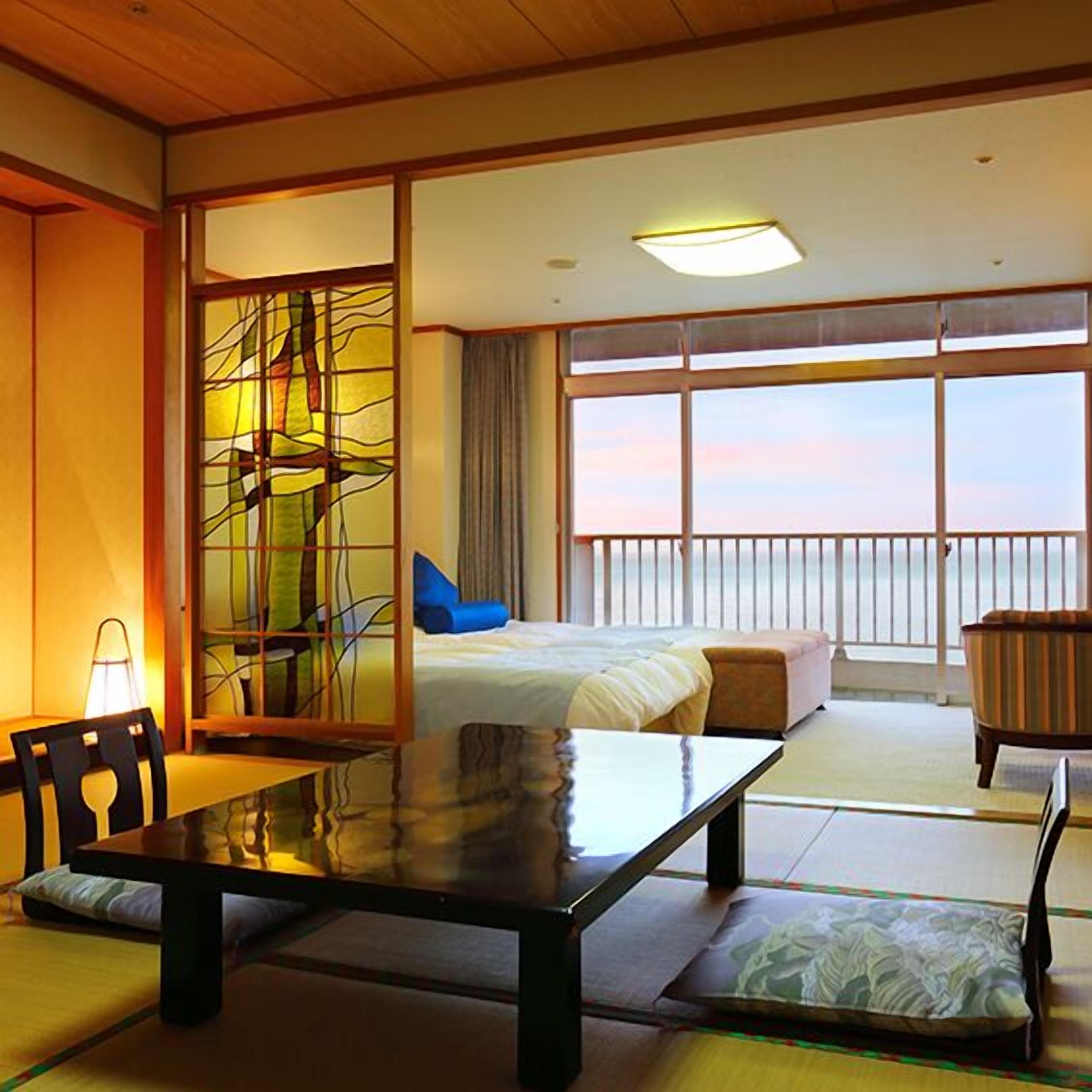 Un cuarto de hotel con una cama, una mesa de comedor, una silla, un sofá y vista al mar.