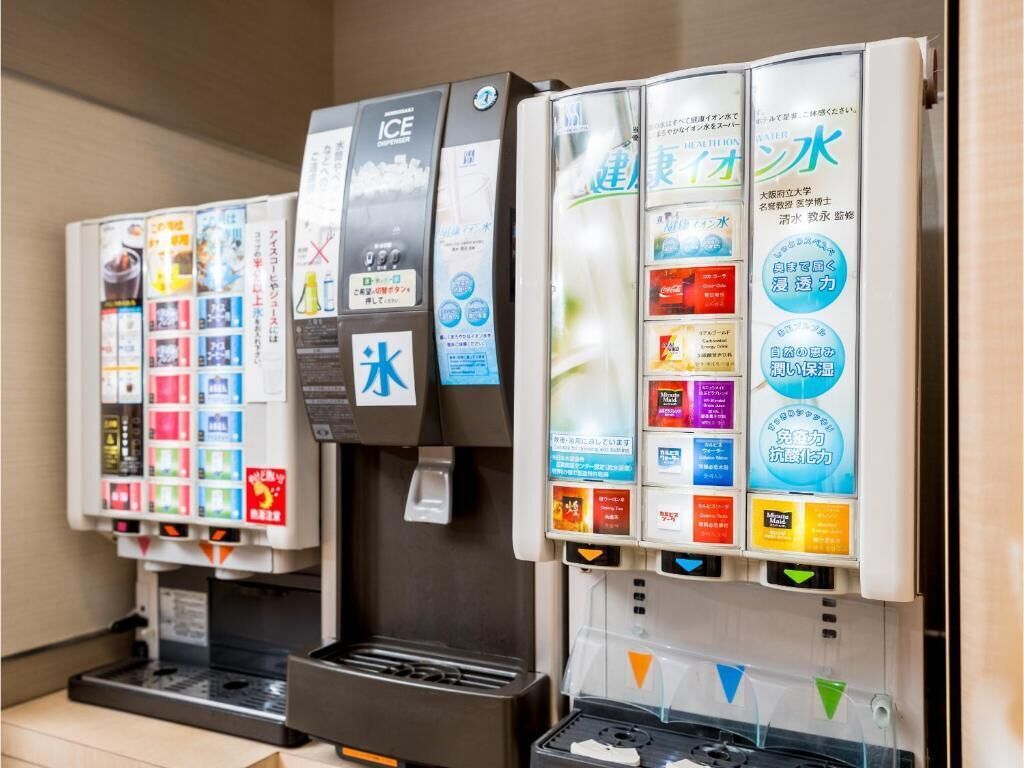 Una hilera de dispensadores de bebidas con distintas opciones y etiquetas promocionales.