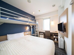 Habitación de hotel con literas, un escritorio con silla, televisión y ventana.