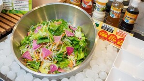 A salad bowl on a table with condiments and a menu in the background. - Super Hotel Hachinohe Natural Hot Springs (Hachinohe)
