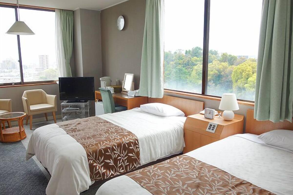 Une chambre d’hôtel avec deux lits, une télévision, un bureau et une chaise.