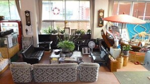 Een zithoek met een bank, salontafel, ventilator en verschillende potplanten.
