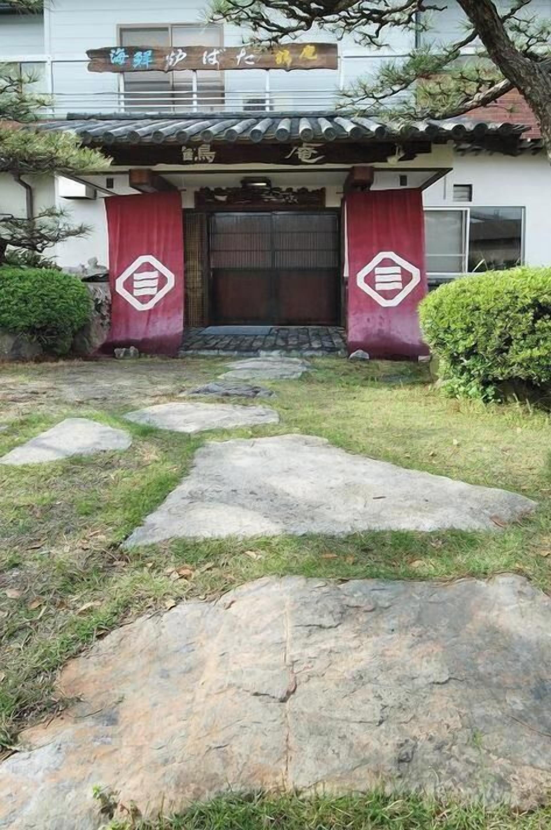 A traditional Japanese building with a tiled roof and a stone pathway leading to the entrance.