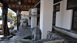 Ein traditioneller japanischer Eingangsbereich mit einem Kiesweg, der zu einem Gebäude führt.