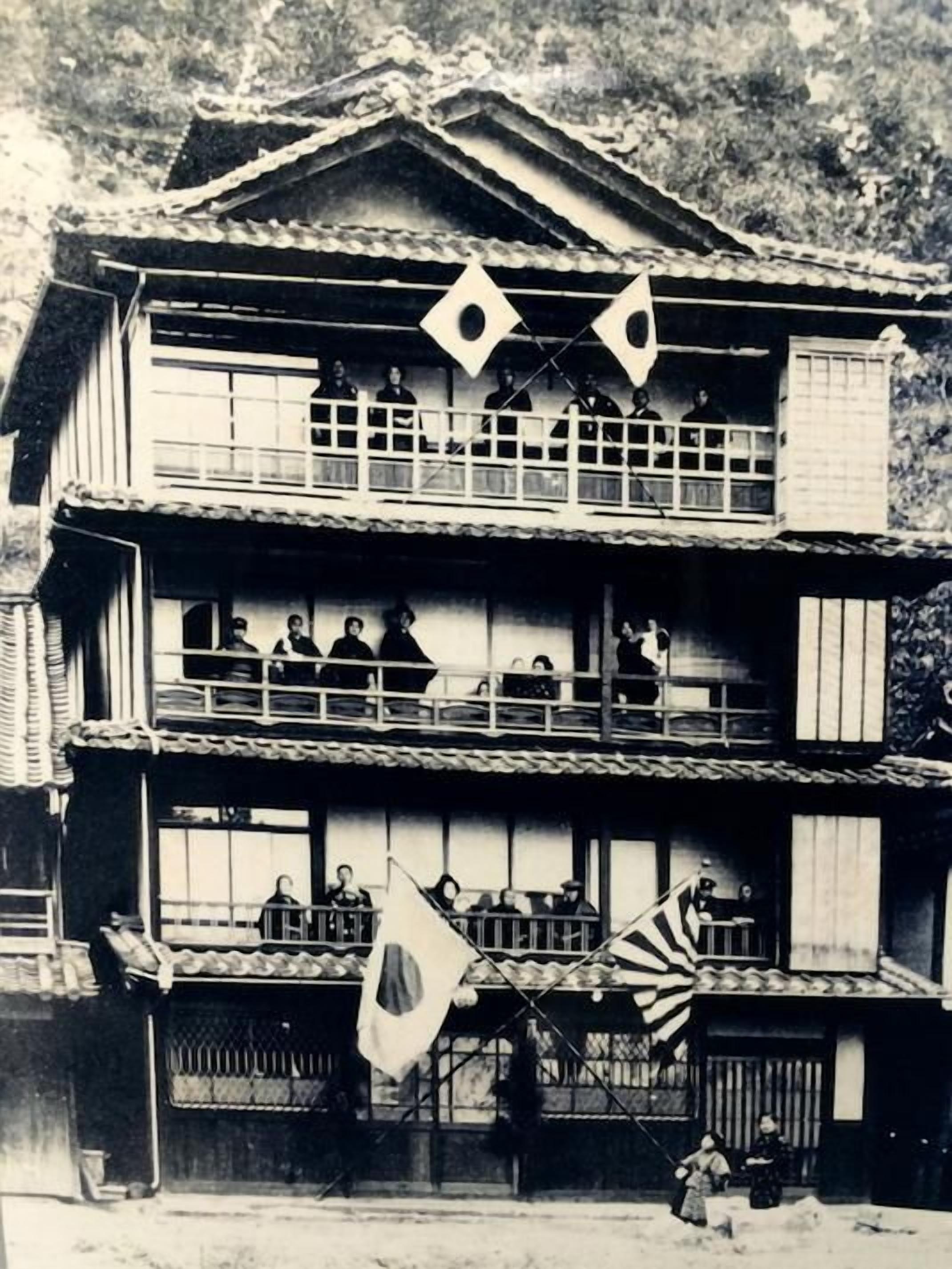 Um edifício tradicional de vários andares, com telhado em tijolos e varanda no andar superior.