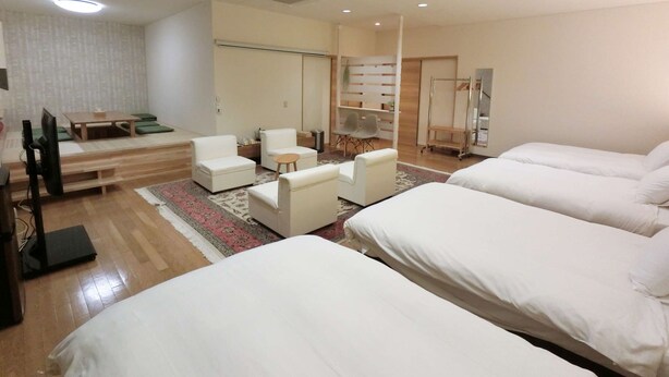 Una habitación de hotel con dos camas, un sofá, un televisor y una mesita.