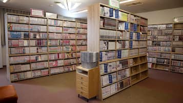 Une bibliothèque avec de nombreuses étagères remplies de livres. Des panneaux indiquent les différentes sections.