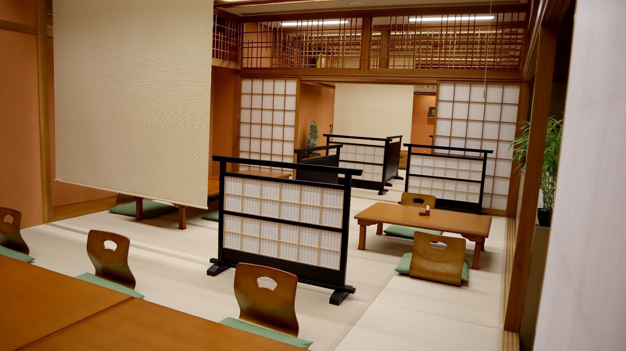 Une pièce de style japonais traditionnel, avec un sol recouvert de tatamis, de petites tables basses et des chaises.
