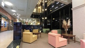 Una hall con zone salotto, una reception e una scala che conduce a un piano superiore.