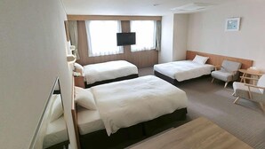Habitación de hotel con dos camas, televisión, escritorio y una silla.