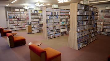 A library with multiple bookshelves, seating areas, and a wooden column.