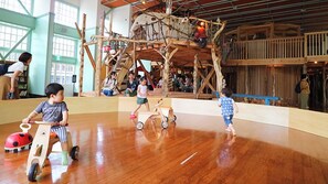A wooden play structure with a slide and climbing area, surrounded by a polished wooden floor. - Honjo Grand Hotel (Yurihonjo)