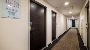 A hotel corridor with dark wooden doors, a carpeted floor, and a sign indicating room numbers. - Super Hotel Yokkaichi Kokudoichigozoi (Yokkaichi)