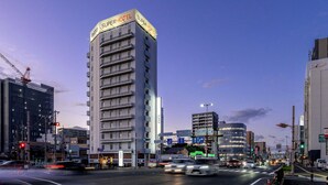 A multi-story hotel with a prominent sign, a busy urban street, and surrounding buildings. - Super Hotel Yokkaichi Kokudoichigozoi (Yokkaichi)