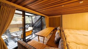 A cozy cabin interior with a wooden ceiling, a large bed, a sofa, and a dining table. - Glamping Spa Waita (Oguni)