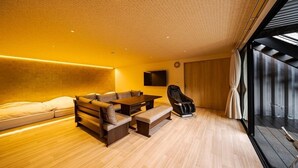 A modern living room with a sofa, a coffee table, and a recliner. - Glamping Spa Waita (Oguni)