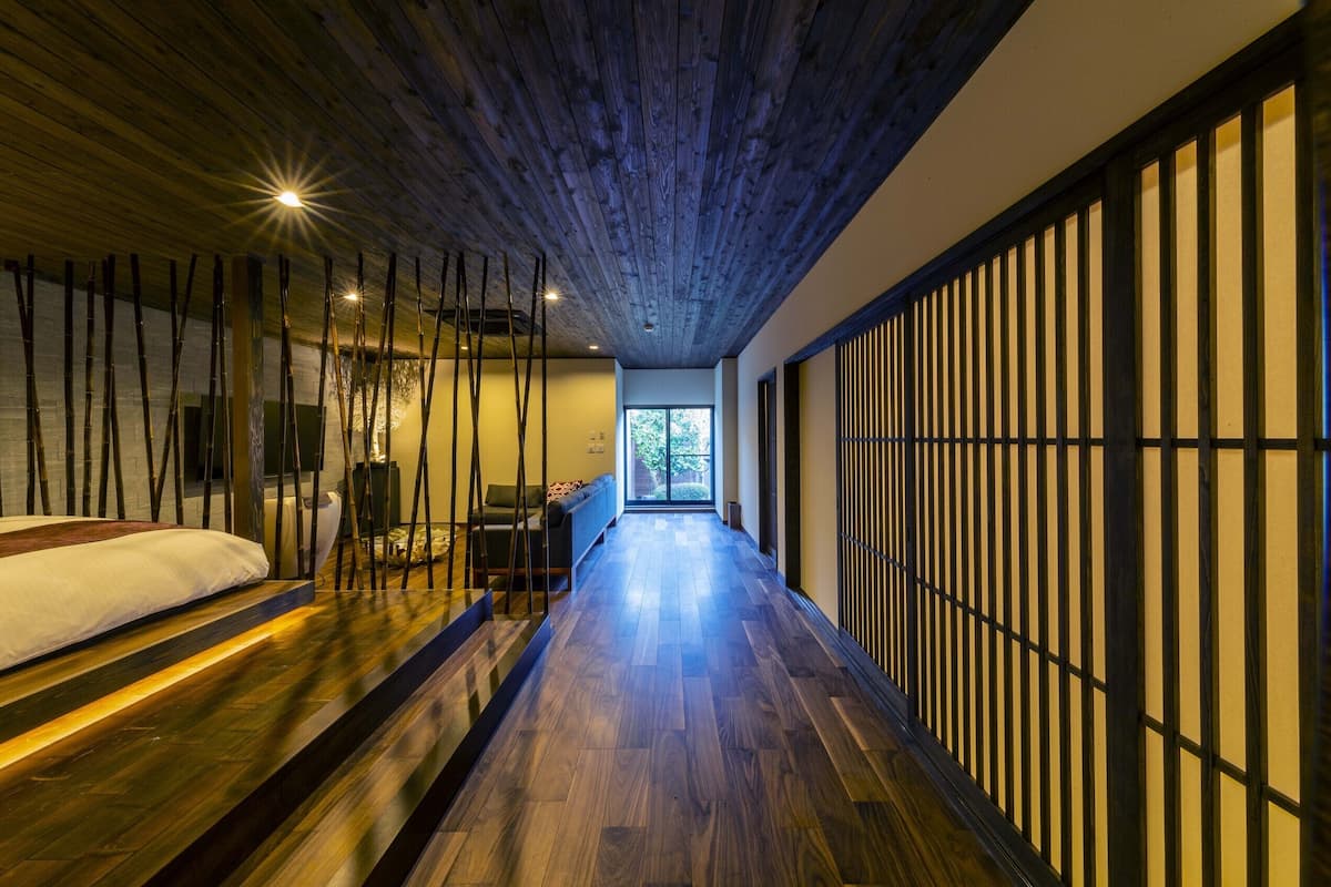 Een modern interieur met een houten vloer, een bed, een bank en een schuifdeur.