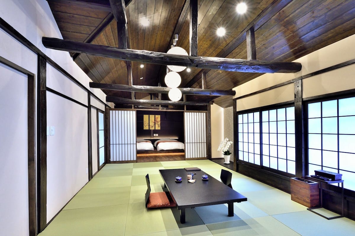 Una habitación japonesa tradicional con suelo de tatami, una mesa baja y puertas correderas.