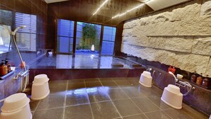 Un baño moderno con pared de piedra, un ventanal grande y zona de ducha.