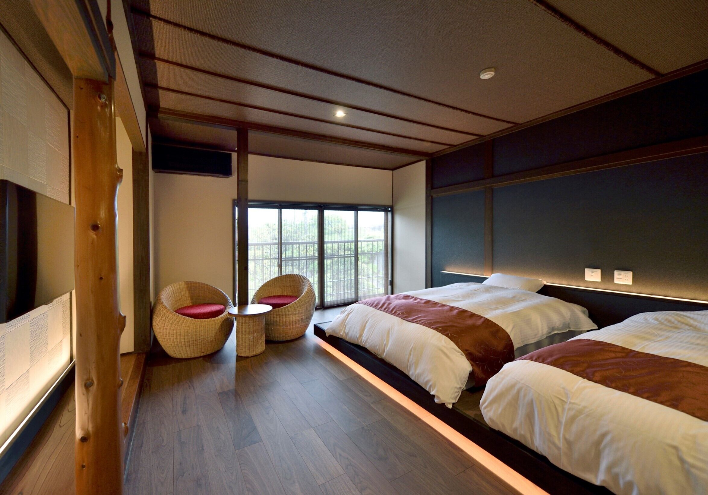Una habitación de hotel moderna con una cama grande, dos mesitas de noche, una ventana y suelo de madera.