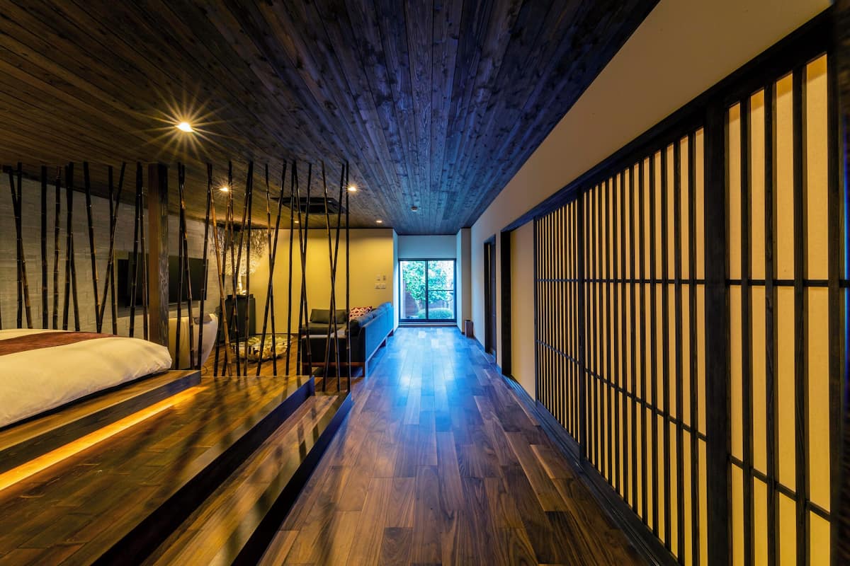 Une chambre d’hôtel moderne avec un plancher en bois, un lit, un coin salon et une vue sur l’extérieur.