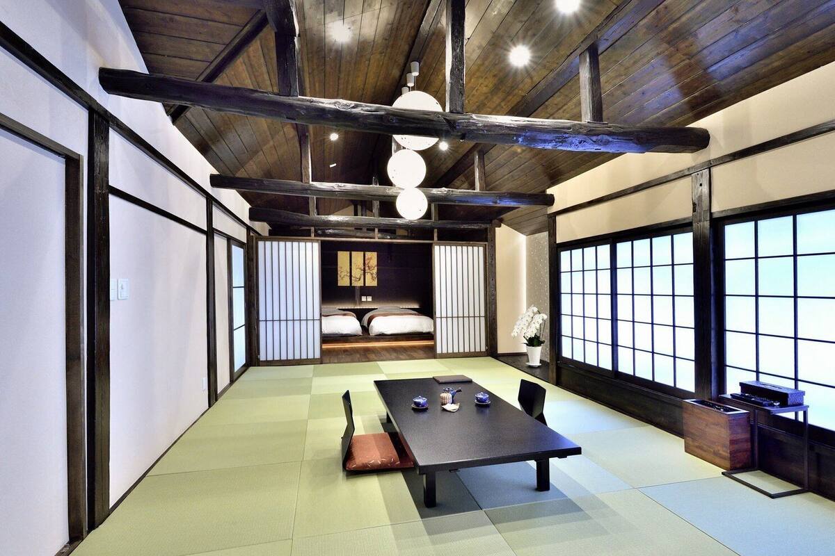 Une pièce de style japonais traditionnel, avec un sol recouvert de tatamis, une table basse et un futon servant de lit.