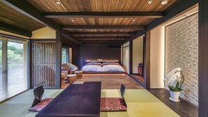Una habitación tradicional japonesa con suelo de tatami, un futón con almohadillas, una mesa con cojines y una puerta corredera.