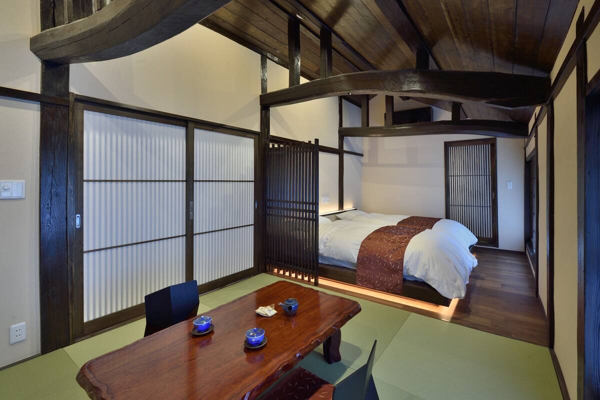 Une pièce de style japonais traditionnel, avec un sol recouvert de tatamis, un lit bas en bois et un paravent coulissant de type shoji.