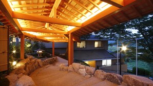 A covered outdoor area with stone steps and wooden beams, overlooking a residential building. - Spa Terrace Shisui (Kobe)
