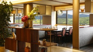 A modern dining area with a wooden table, chairs, and a view of greenery outside. - Spa Terrace Shisui (Kobe)