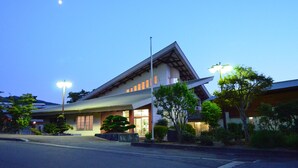 A modern building with a sloped roof and large windows, surrounded by well-maintained greenery.