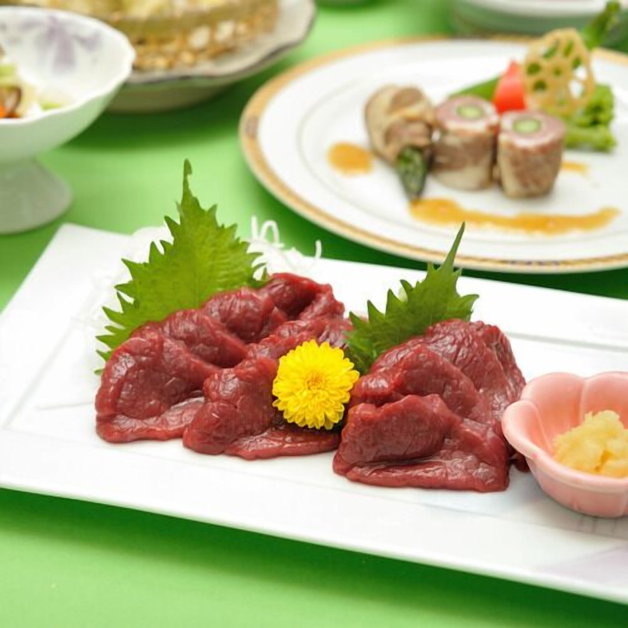 A plate of raw beef with a yellow flower garnish on a white plate.