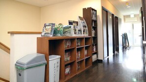 Un couloir avec des étagères en bois remplies de livres, une poubelle et une porte donnant sur une autre pièce.