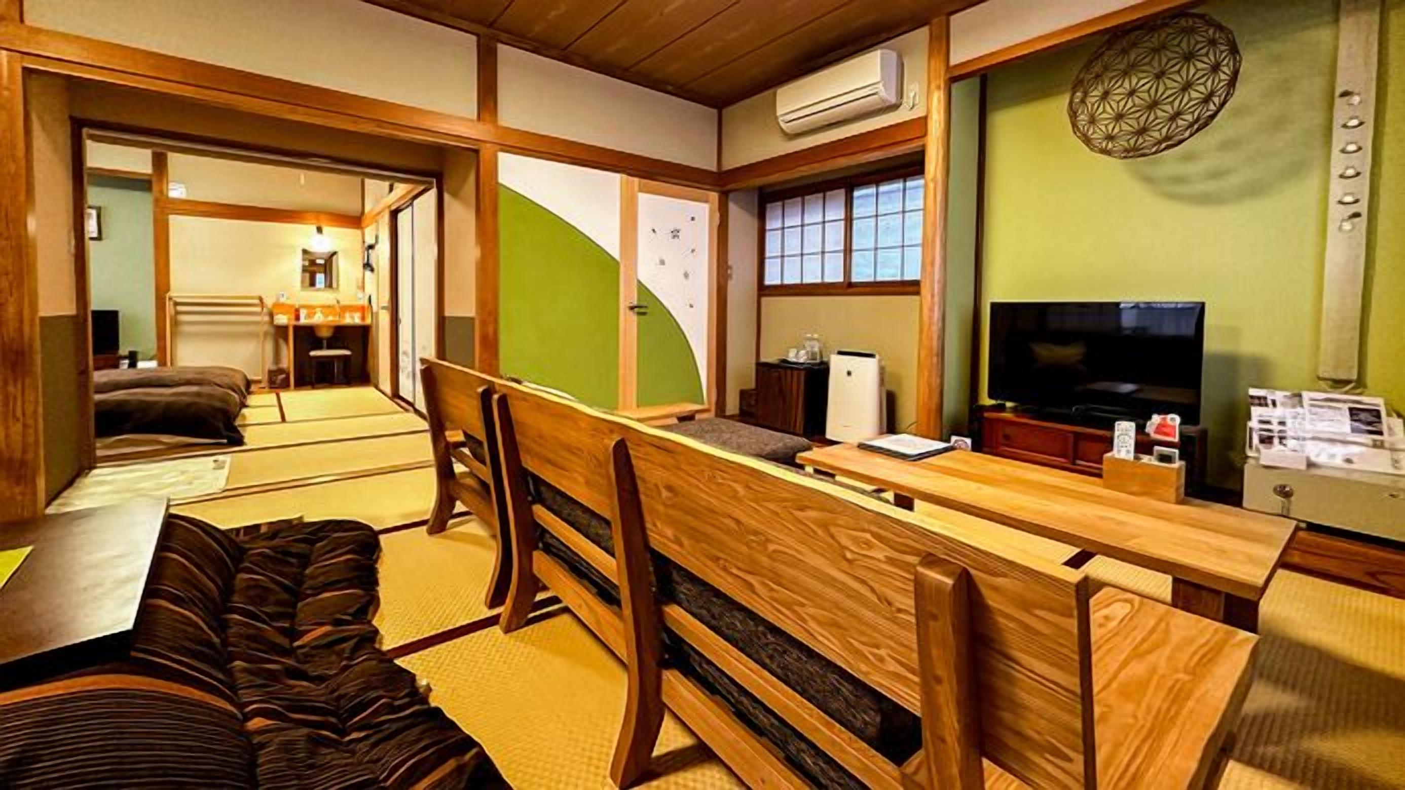 Perinteinen japanilaistyylinen huone, jossa on tatamimatto, matala puupöytä ja televisio.