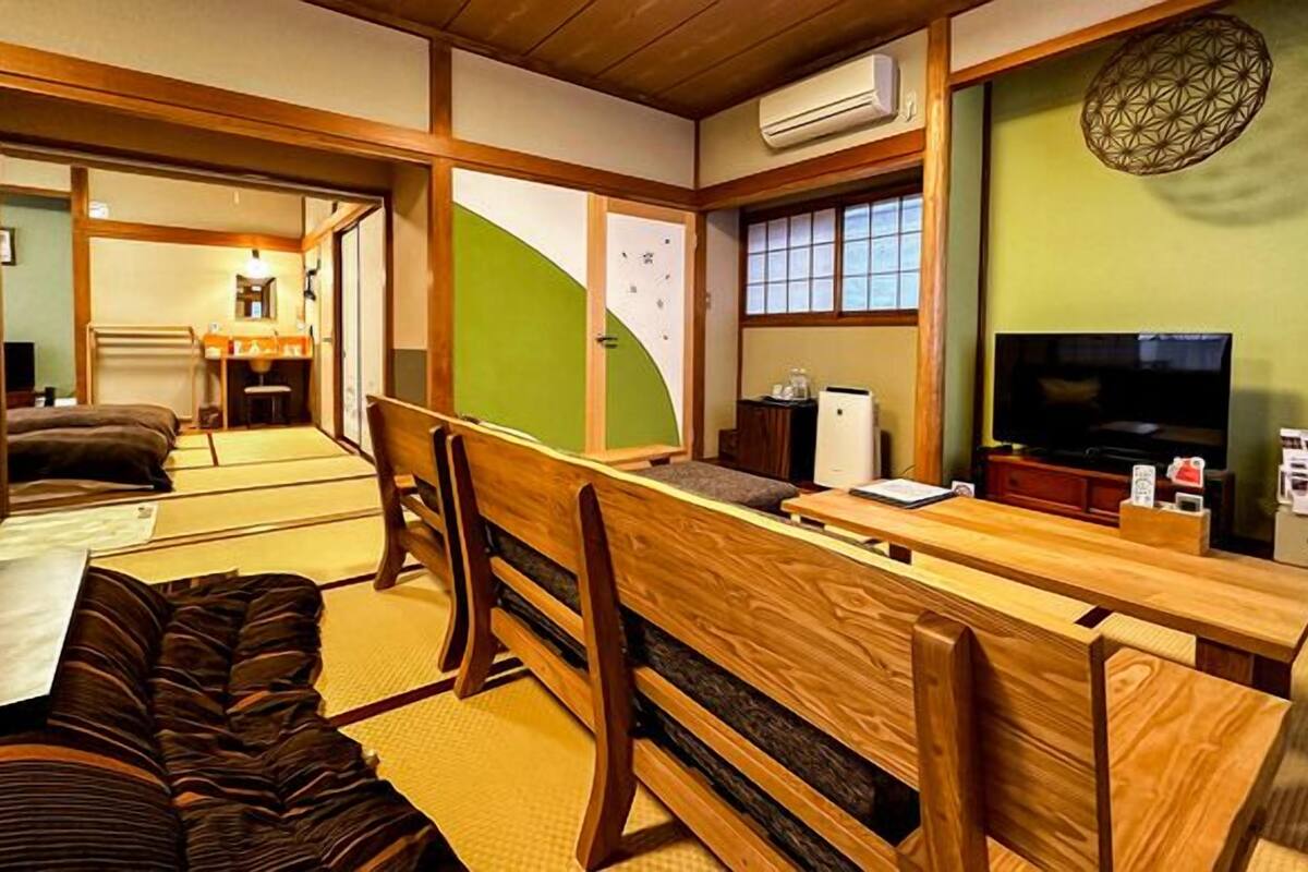 Um quarto tradicional japonês com tatames, uma mesa de madeira baixa e uma televisão.