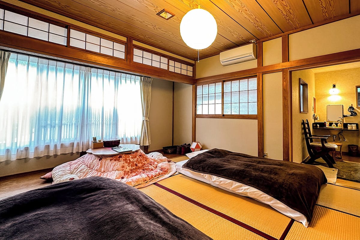 Quarto japonês tradicional com tatames, duas camas, uma escrivaninha e um espelho.