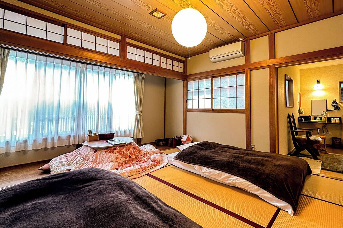 Perinteinen japanilainen huone, jossa on tatamimatto, kaksi sänkyä, työpöytä ja peili.