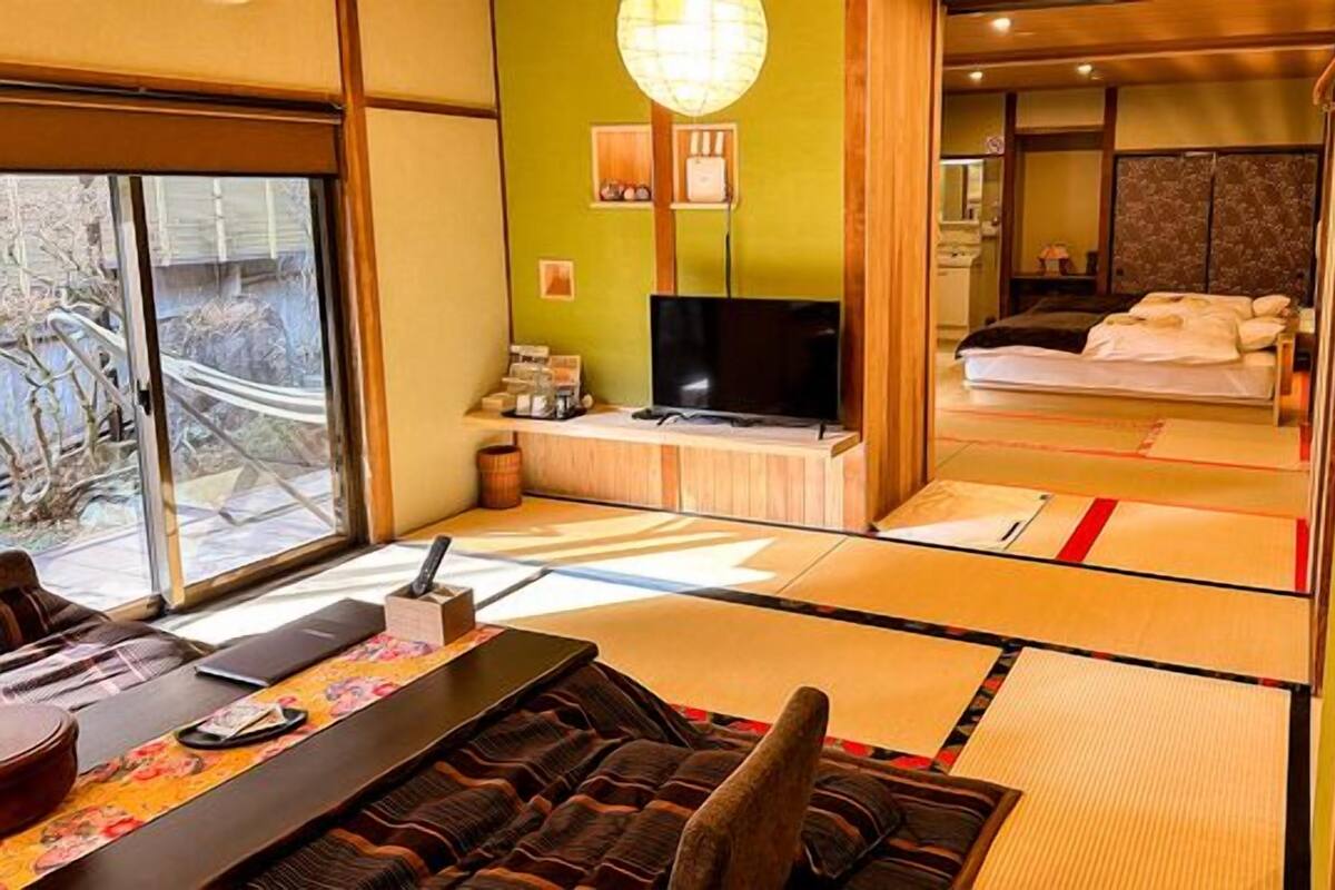 Quarto japonês tradicional com tatames, televisão e cama com futons.